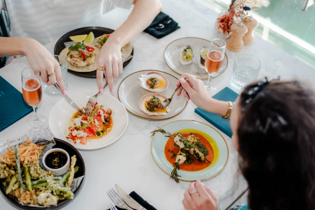 Top down shot of peoples hand while they help themselves to food from the table. Shot by Luxwerk photography in Perth