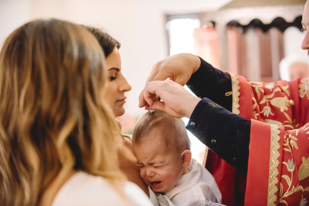 Orthodox priest cutting hair of the baby at baptiism